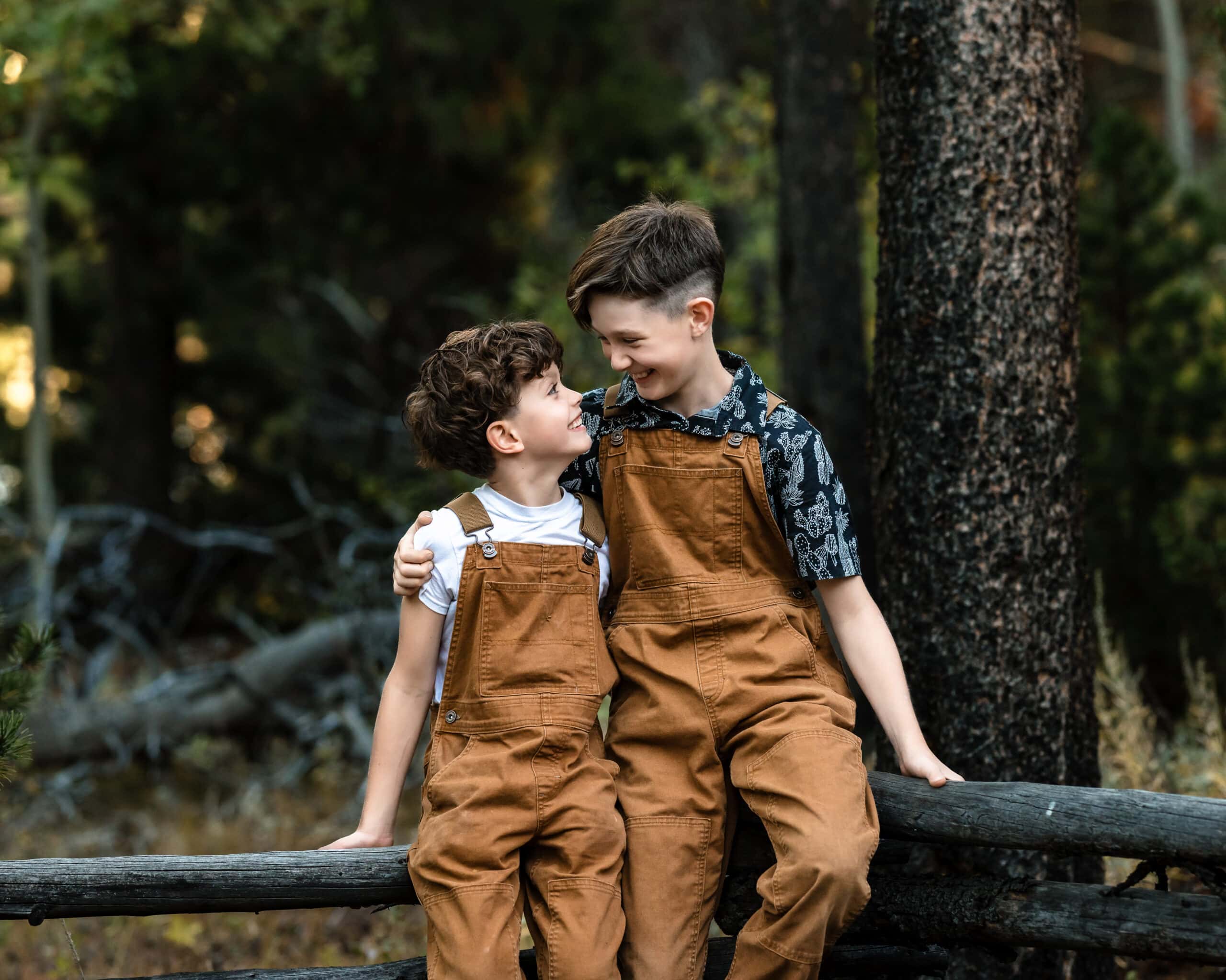 Brothers in matching overalls share a sweet Boulder forest family portrait.