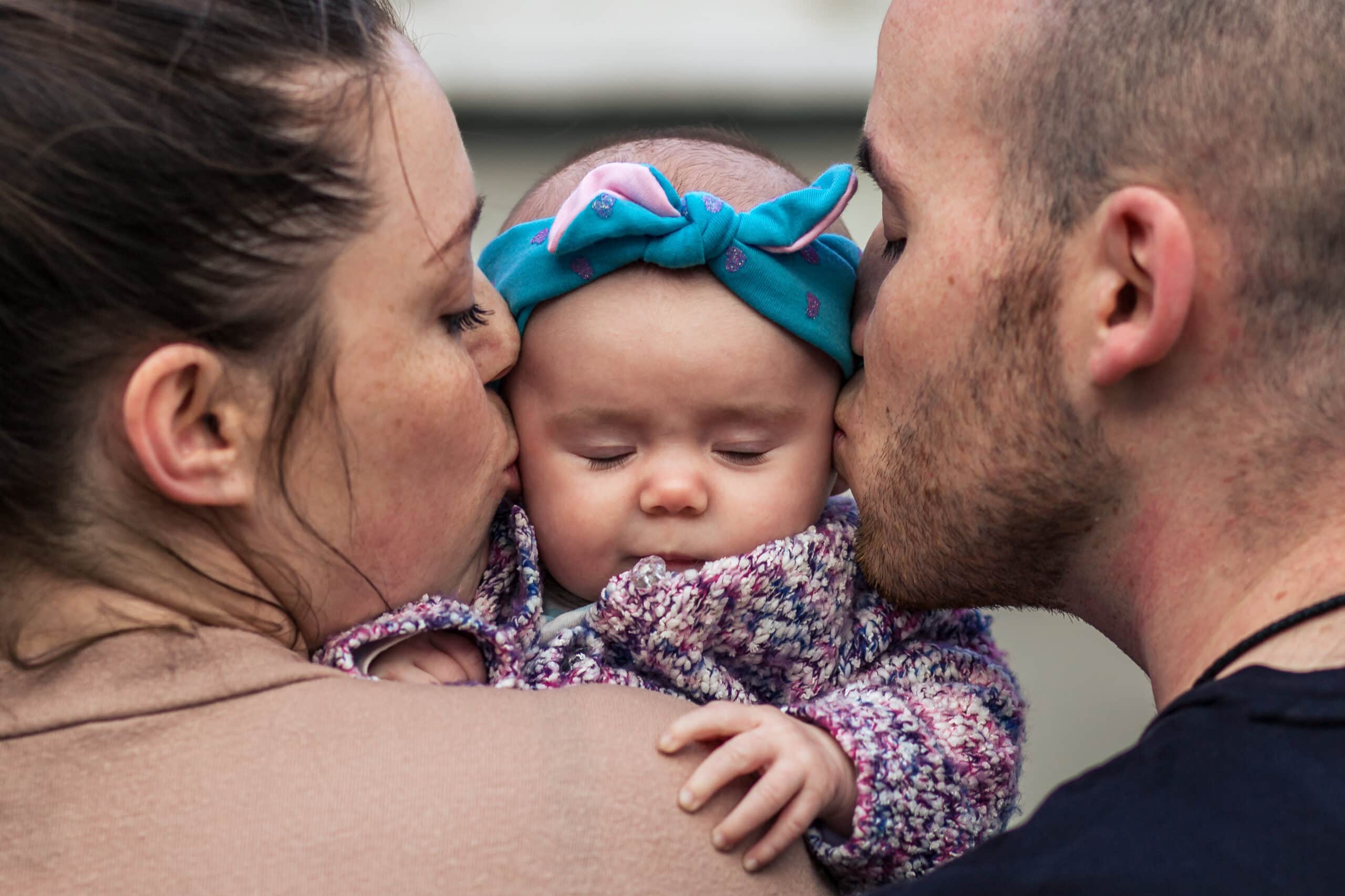 Colorado newborn portrait of parents kissing their sleeping baby at home