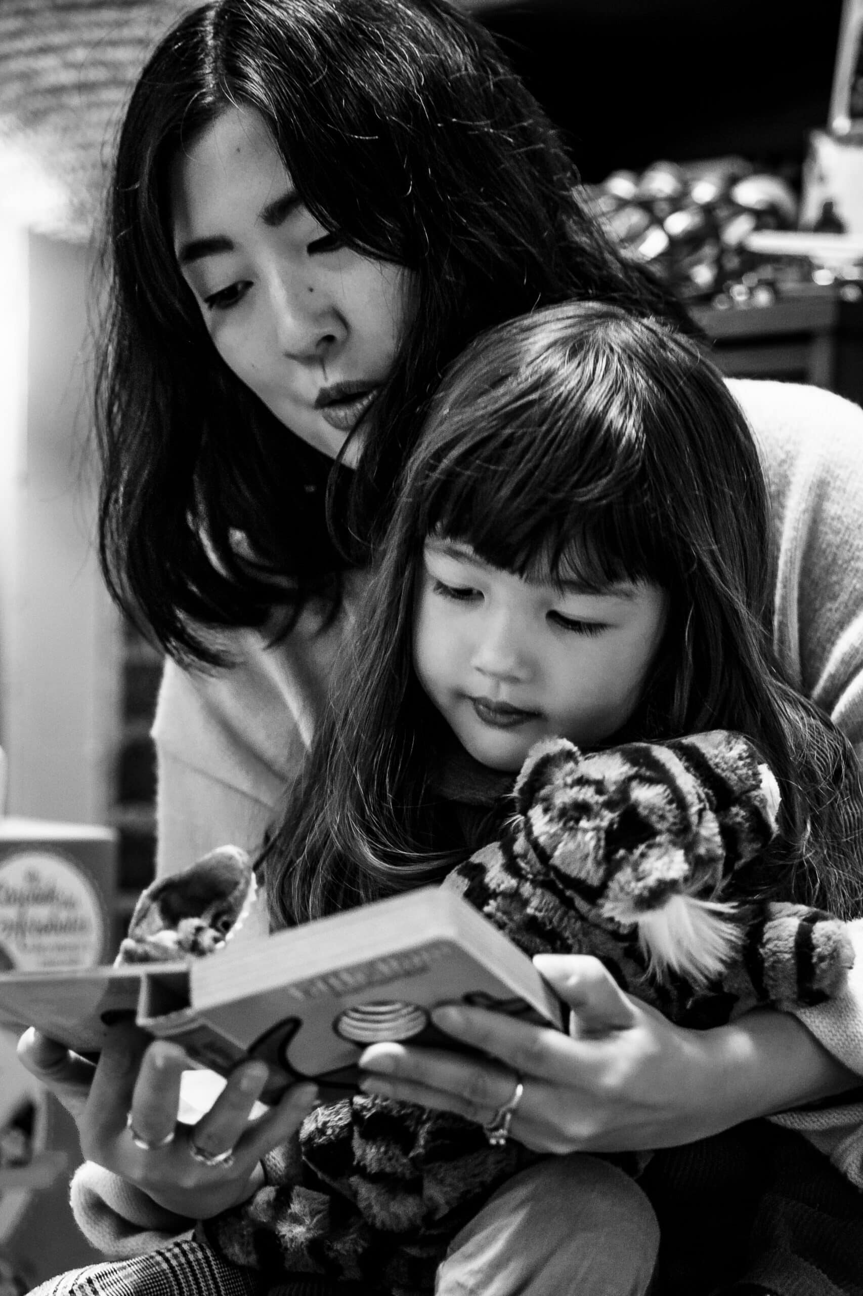 Black-and-white photo of parent and child reading together