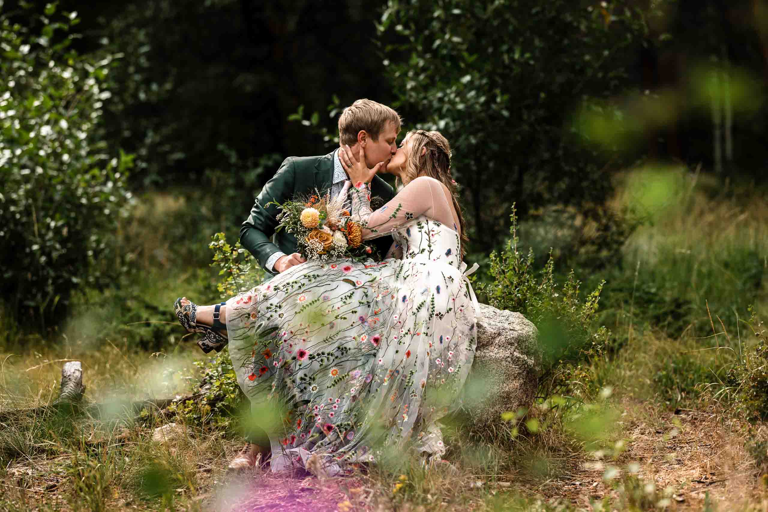 A newlywed couple kissing on a rock in Rocky Mountain National Park