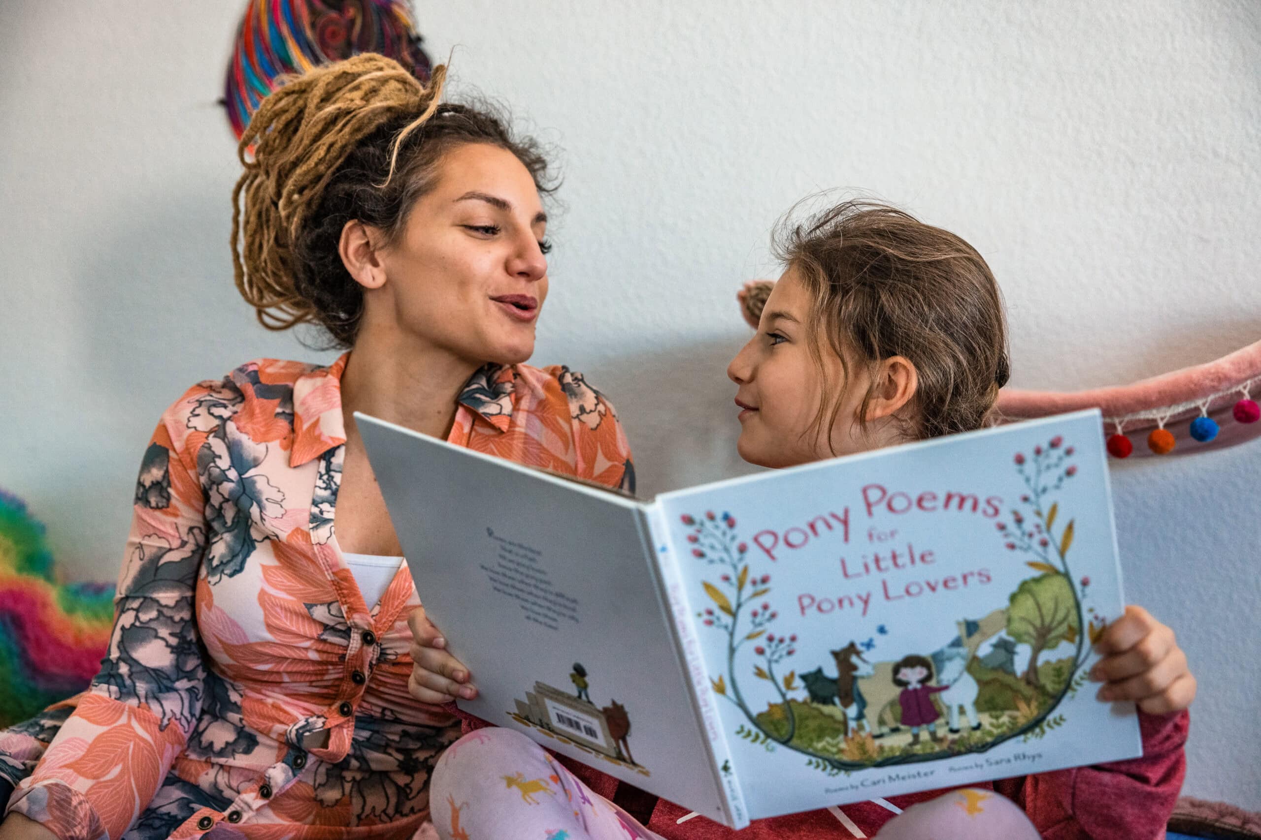 A little girl reading a book to her mom during a documentary family photography session.