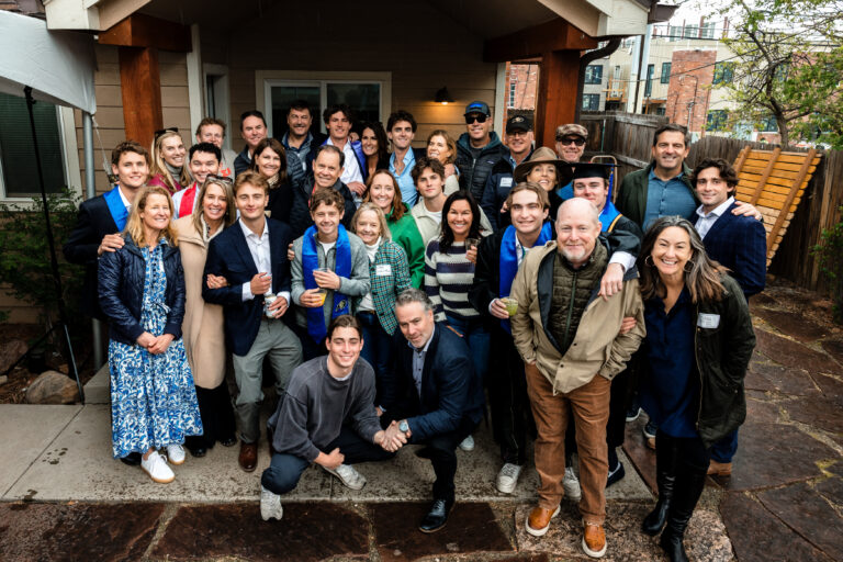 Boulder Senior Photographer captures cheerful graduation group on wet steps outside rustic building