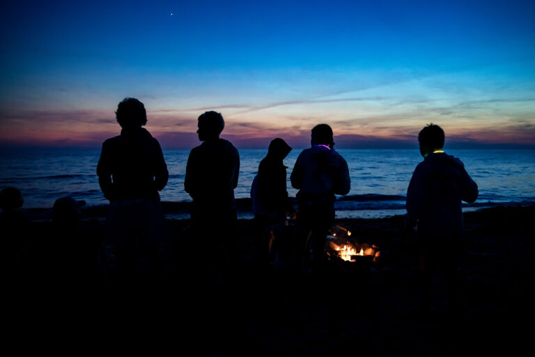 Documentary family photography session with silhouetted beach bonfire at dusk.