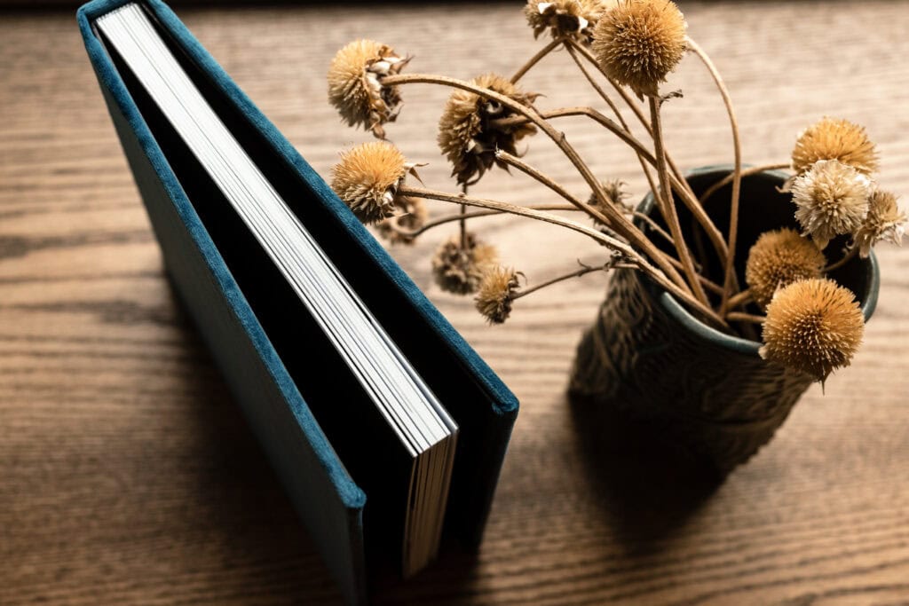 Photography Services still life with teal book and dried flowers on wooden table