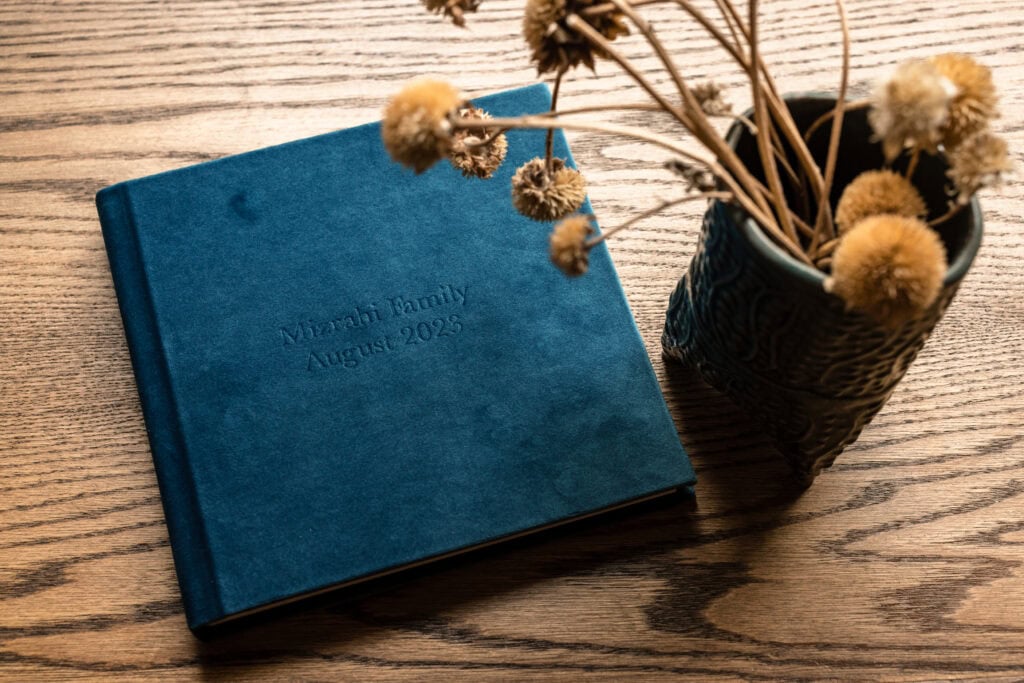 Teal photo album with dried flowers on wooden table for Photography Services