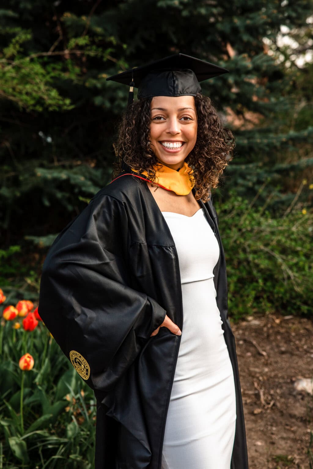 Colorado Senior Pictures: smiling graduate in cap and gown among tulips.