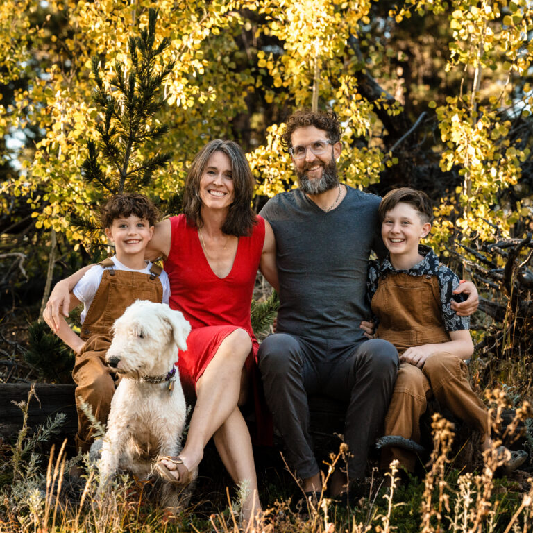 Outdoor family portrait with dog in sunlit golden woods