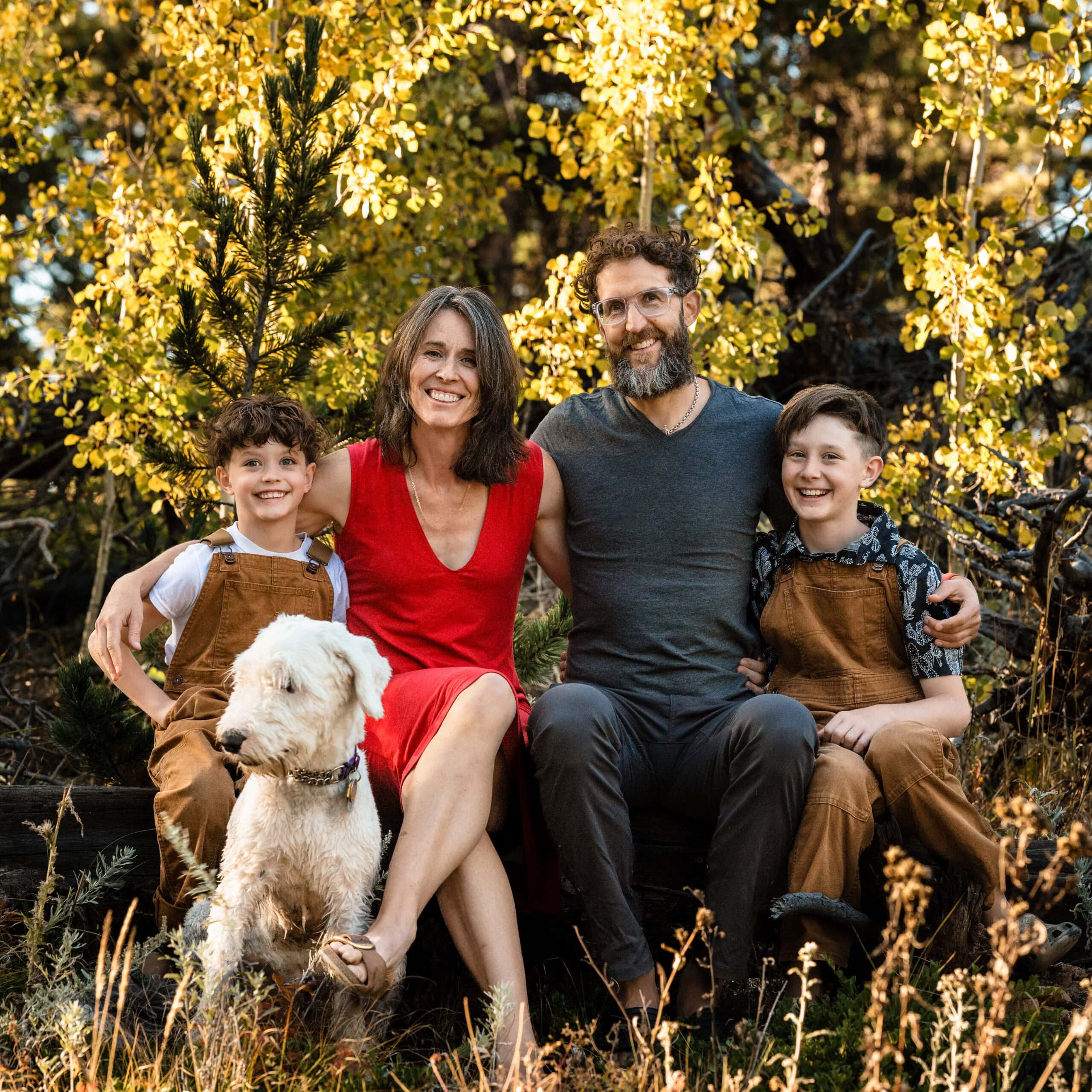 Outdoor family portrait with dog in sunlit golden woods