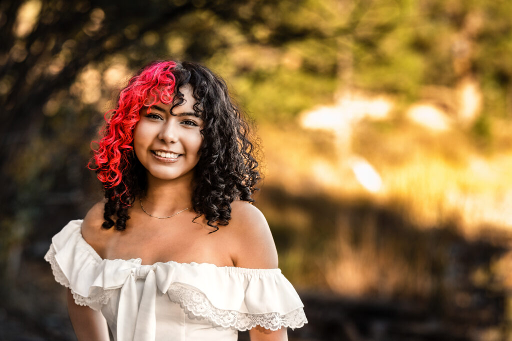 Senior photographer Boulder Colorado golden hour portrait of smiling graduate with red-streaked curls