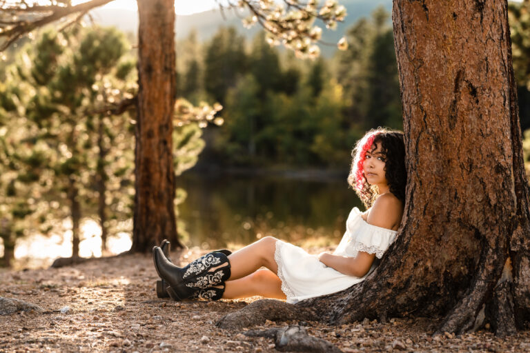 Senior photographer Boulder Colorado portrait of young woman in white dress by pine lake