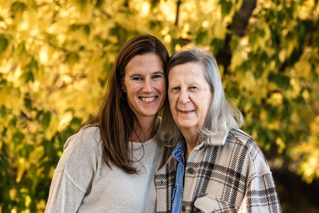 Two generations smile during Fall Family Mini Sessions Colorado among golden autumn leaves.