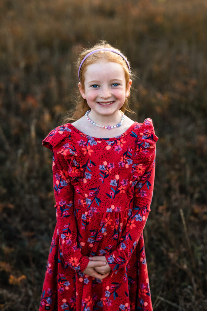 Smiling child in red floral dress at Fall Family Mini Sessions Colorado