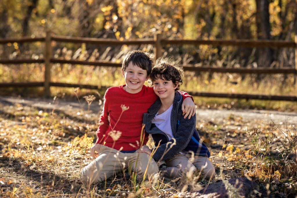Two smiling children at Fall Family Mini Sessions Colorado in golden autumn light