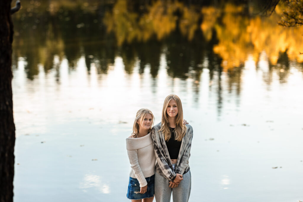 Fall Family Mini Sessions Colorado with two young women by an autumn lake.