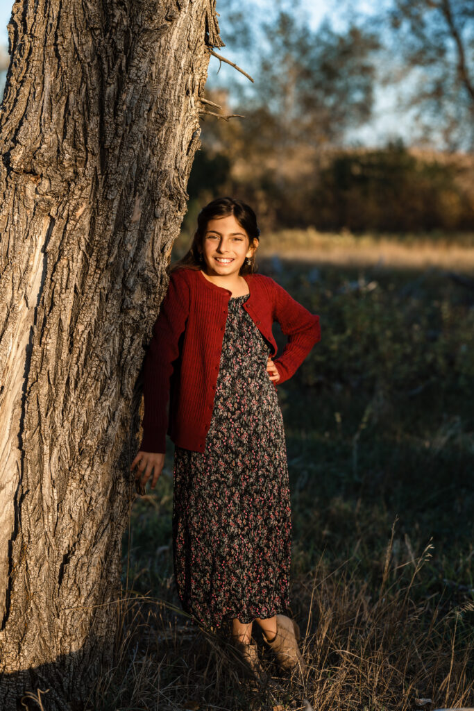 Girl by sunlit tree during Fall Family Mini Sessions in Colorado