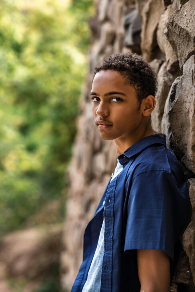 Senior portrait by Boulder Colorado photographer, student leaning against stone wall in natural light.
