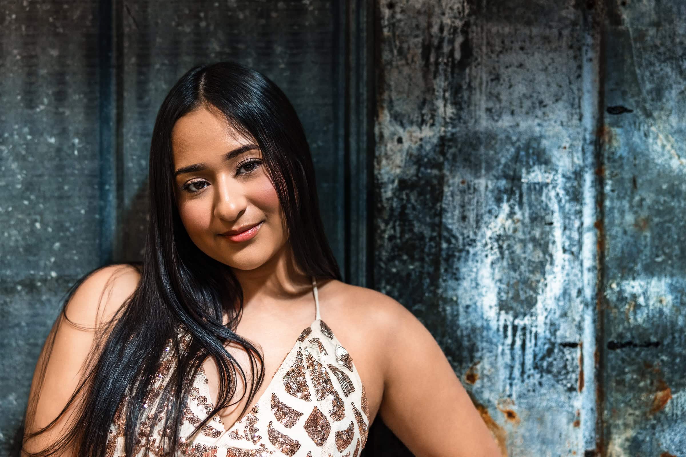 Colorado Senior Pictures portrait of smiling girl against weathered industrial blue-gray metal backdrop